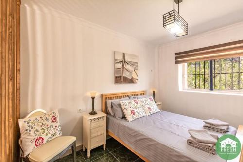 um quarto com uma cama, uma cadeira e uma janela em Town house with jacuzzi and foosball table em Viñuela