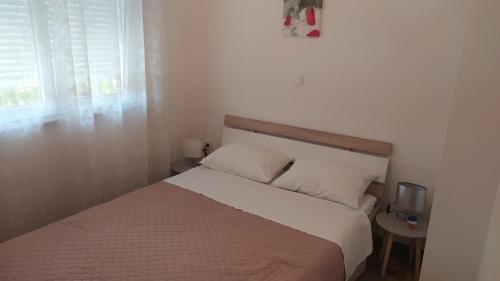 un dormitorio con una cama y una ventana en Apartman Greta Sukošan, en Sukošan