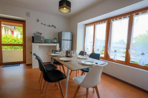 une salle à manger avec une table, des chaises et des fenêtres dans l'établissement L'Écrin Vue Lac 3 étoiles - Parking gratuit, Calme & confort, à Sévrier