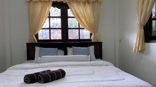 a bedroom with a large white bed with a window at Vacation Home Tambon Karon in Karon Beach