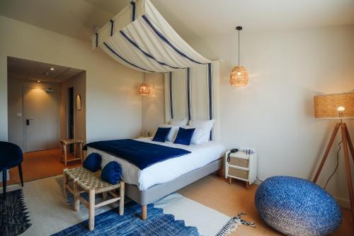a bedroom with a large bed with a blue blanket at Hôtel Le Noirmoutier in Barbâtre
