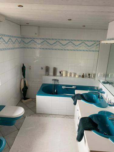 a bathroom with two sinks and a blue tub at Nabo Ferienwohnung Lechbruck in Lechbruck