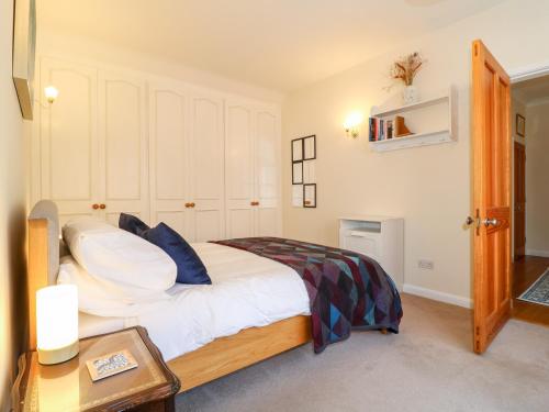 a bedroom with a bed with white sheets and blue pillows at Elm Tree Cottage in Melton Mowbray