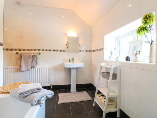 a bathroom with a sink and a bath tub and a mirror at Elm Tree Cottage in Melton Mowbray