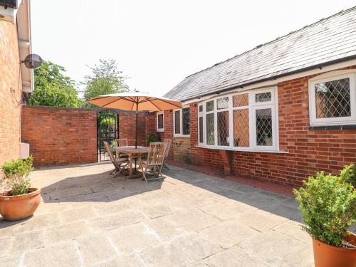 a patio with a table and an umbrella at Elm Tree Cottage in Melton Mowbray
