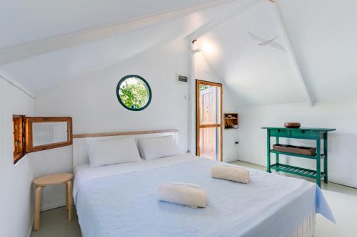a white bedroom with a bed and a green table at #Pinetree Cabin by halu! Villas in Kalandra