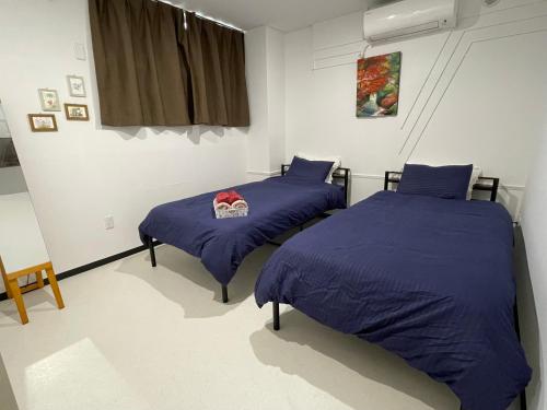 twee bedden in een kamer met blauwe lakens bij Zenibako House 1f in Otaru