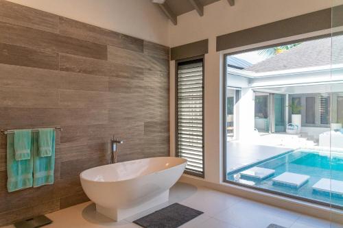 a bathroom with a tub and a swimming pool at VIP The Beach House in Jolly Harbour