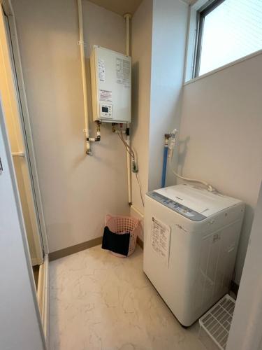 een wasruimte met een wasmachine en een raam bij Zenibako House 1f in Otaru