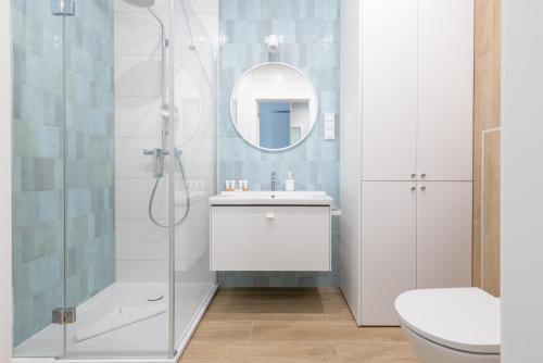 a bathroom with a shower and a sink and a mirror at Apartment Polanki Aqua Kołobrzeg by Renters Prestige in Kołobrzeg