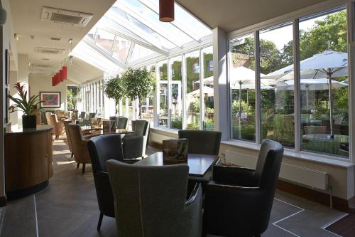 a dining room with tables and chairs and windows at The Bull in Gerrards Cross