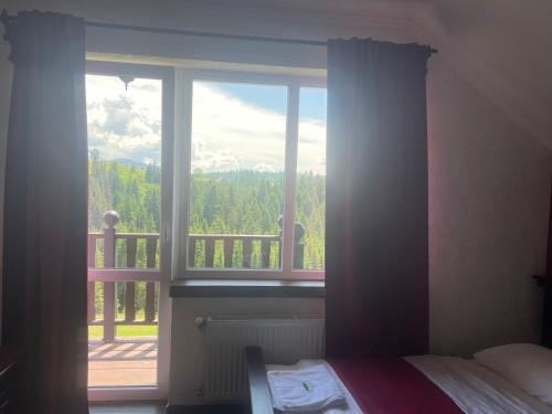 a bedroom with a window with a view of a balcony at Мелодія Гір Вид на гори in Vorokhta
