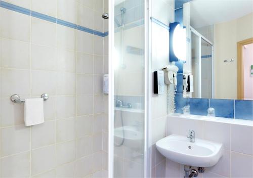 La salle de bains blanche est pourvue d'un lavabo et d'un miroir. dans l'établissement Campanile Villefranche-Sur-Saône, à Villefranche-sur-Saône