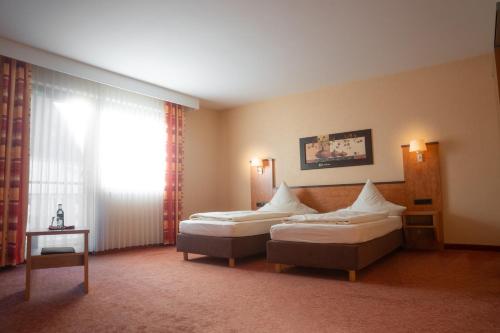 a hotel room with two beds and a window at Hotel Gasthof Käßer in Ansbach