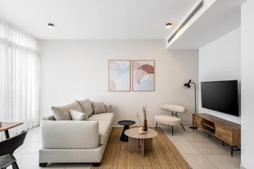 a living room with a couch and a tv at Mate TLV PORT - By HOMY in Tel Aviv