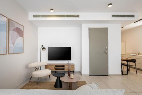 a living room with a television and a table and chairs at Mate TLV PORT - By HOMY in Tel Aviv