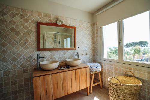 ein Badezimmer mit zwei Waschbecken auf einem Holzschrank in der Unterkunft Hôtel Le Noirmoutier in Barbâtre