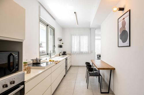 a kitchen with white cabinets and a wooden table at Mate TLV PORT - By HOMY in Tel Aviv