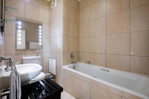 ein Badezimmer mit Badewanne und Waschbecken in der Unterkunft Sancta South Coast 2 bedroom Apartment in Kingsborough