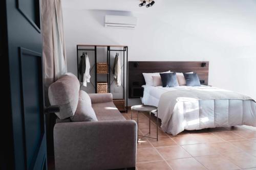 Nido Baeza Suites في بايزا: غرفة نوم بسرير وكرسي وأريكة