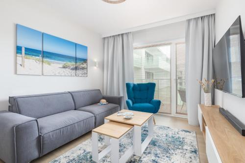a living room with a couch and a blue chair at Apartamenty Polanki Aqua BASENY & SPA Kołobrzeg by Renters Prestige in Kołobrzeg