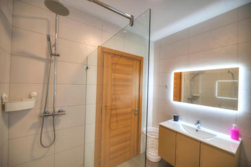 ein Bad mit einer Dusche, einem Waschbecken und einem Spiegel in der Unterkunft Spacious & Tastefully furnished 3 bedrooms RCUT1-1 in Is-Swieqi