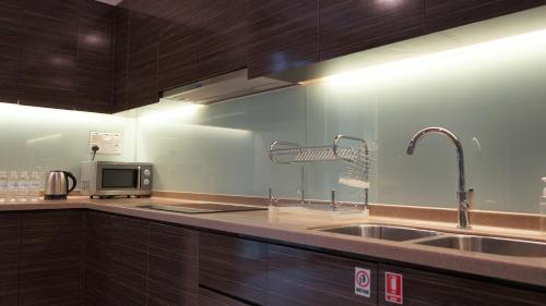 a kitchen with a sink and a microwave at Marina Puteri Harbour Johor by Perfect Host in Nusajaya