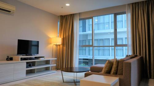 a living room with a couch and a large window at Marina Puteri Harbour Johor by Perfect Host in Nusajaya