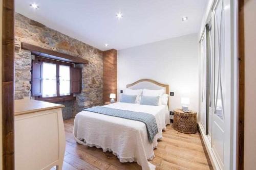 a bedroom with a large bed and a stone wall at Apartamento Playa de Luanco Lux in Luanco