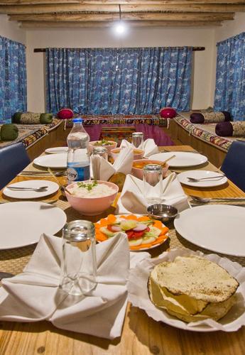 a long wooden table with plates of food on it at Pangong Retreat Camp in Spangmik