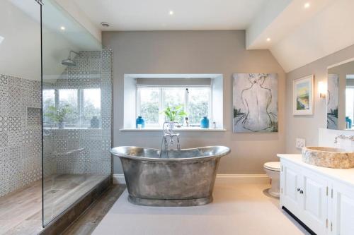 Un baño con bañera grande y ducha. en Country Manor House near Tetbury, en Malmesbury