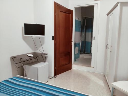 a bedroom with a bed and a television and a door at Mare e Sabbia in Alghero