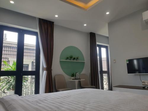 a bedroom with a bed and a tv and windows at Ourhome in Thôn Trường Giang