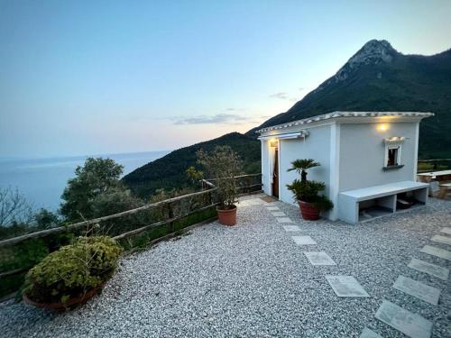 een klein wit huis met een bank op een heuvel bij Amalfi Coast - Mini Cottage vista mare con giardino in Vietri