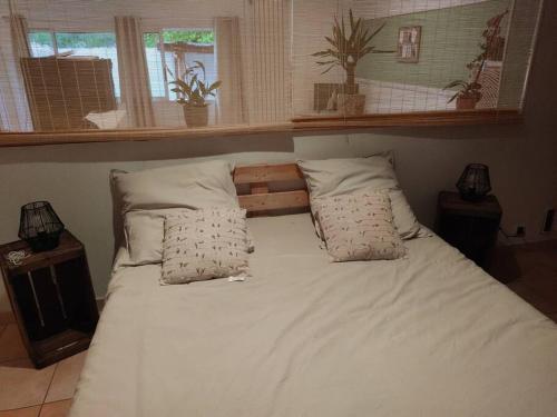 un lit avec des draps blancs et des oreillers dans une chambre dans l'établissement Appartement Velleron-4 personnes, à Velleron