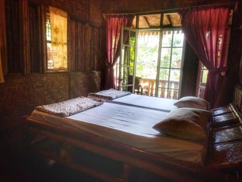 a bedroom with a large bed with a window at ETALAUSER Jungle Gate EcoResort Bukit Lawang in Bukit Lawang