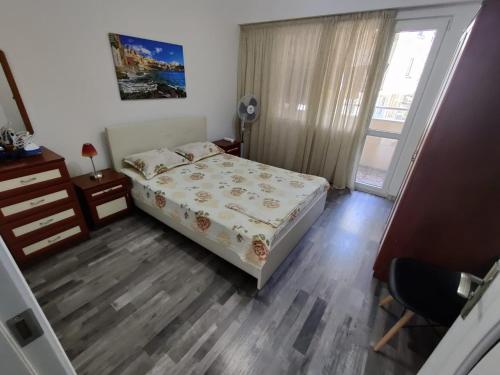 a bedroom with a bed and a desk and a window at Apartment Serkyovi in Pomorie