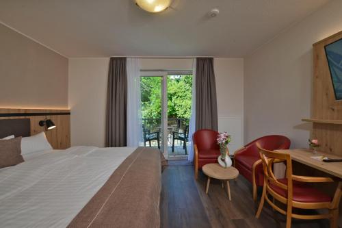 Habitación de hotel con cama, escritorio y sillas en Hotel zur Post 3 Sterne superior en Altenahr