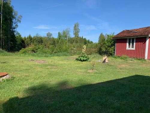 a red barn in a field next to a tree at Großzuegiges Haus im Wald in Immeln