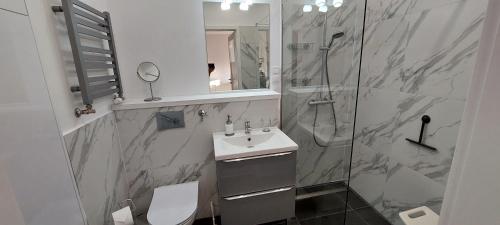 een badkamer met een toilet, een wastafel en een douche bij Apartament Słoneczna z parkingiem in Świnoujście