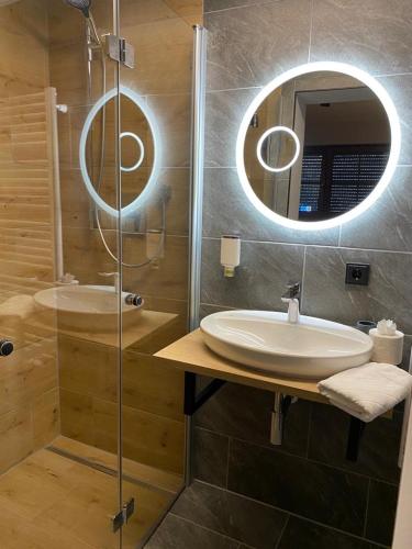 a bathroom with a sink and a shower with a mirror at Hotel Gasthof Käßer in Ansbach