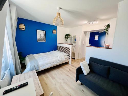Cette chambre bleue comprend un lit et un canapé. dans l'établissement La vie en bleu - Studio proche de Paris, à Charenton-le-Pont