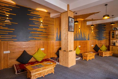 a room with wooden walls and couches and tables at Rainbow Hostelier in Leh
