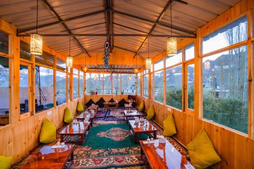 a dining room with wooden tables and windows at Rainbow Hostelier in Leh