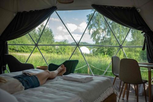 a person laying on a bed in a tent at Biała Czapla Glamping z balią nad jeziorem czorsztyńskim in Maniowy