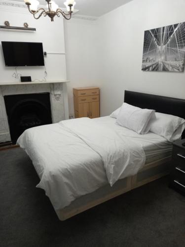 Schlafzimmer mit einem Bett, einem TV und einem Kamin in der Unterkunft Sandra in Streatham Vale