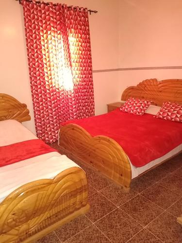 1 dormitorio con 2 camas con sábanas rojas y ventana en Dar badiawarda, en Azilal