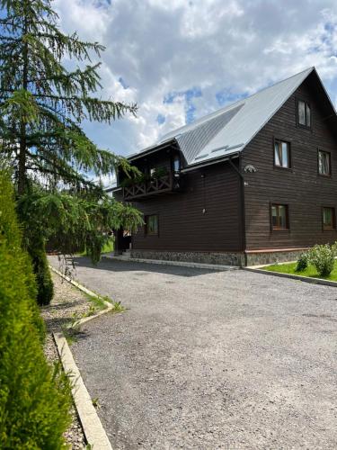 a large wooden barn with a driveway at Guest House in Slavske