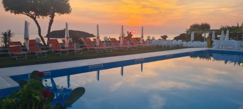 una piscina con sillas y una puesta de sol en el fondo en Hotel Cristina, en Diamante