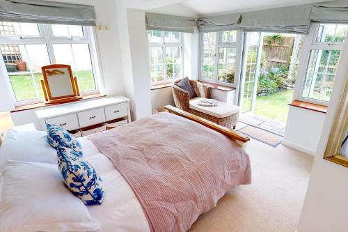 um quarto com uma cama, uma cadeira e janelas em CROYDE HALLGREIN 4 Bedrooms em Croyde